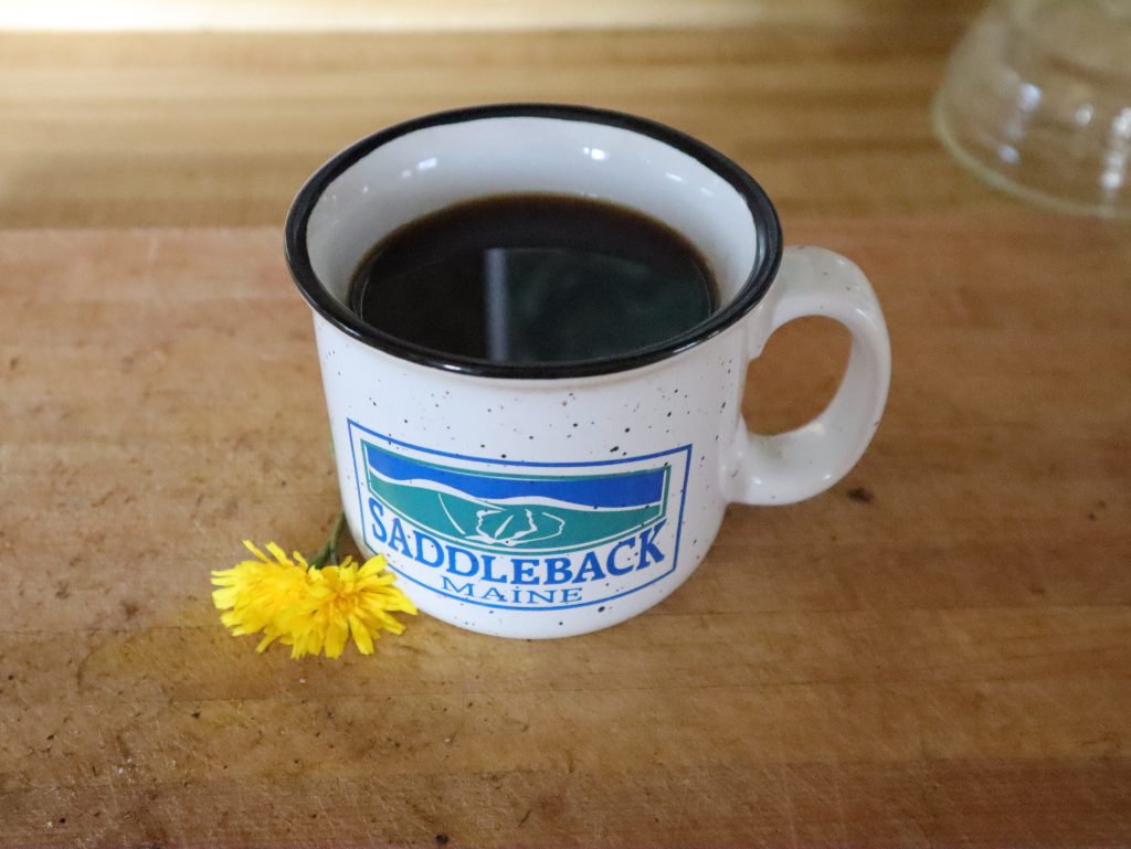 mug of dandelion coffee on counter next to freshly picked dandelions
