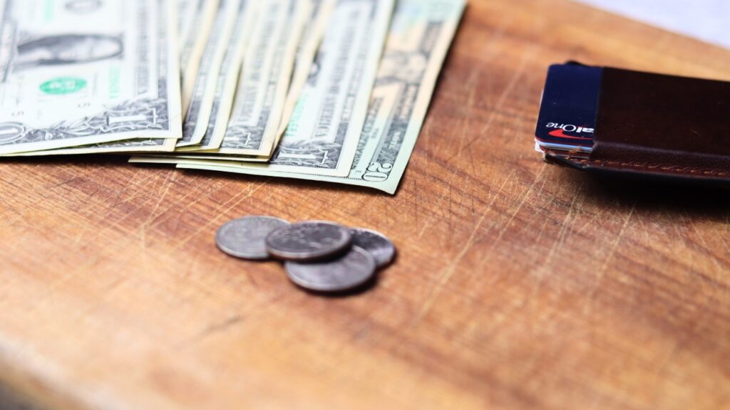 photo of cash, coins and a wallet on a counter